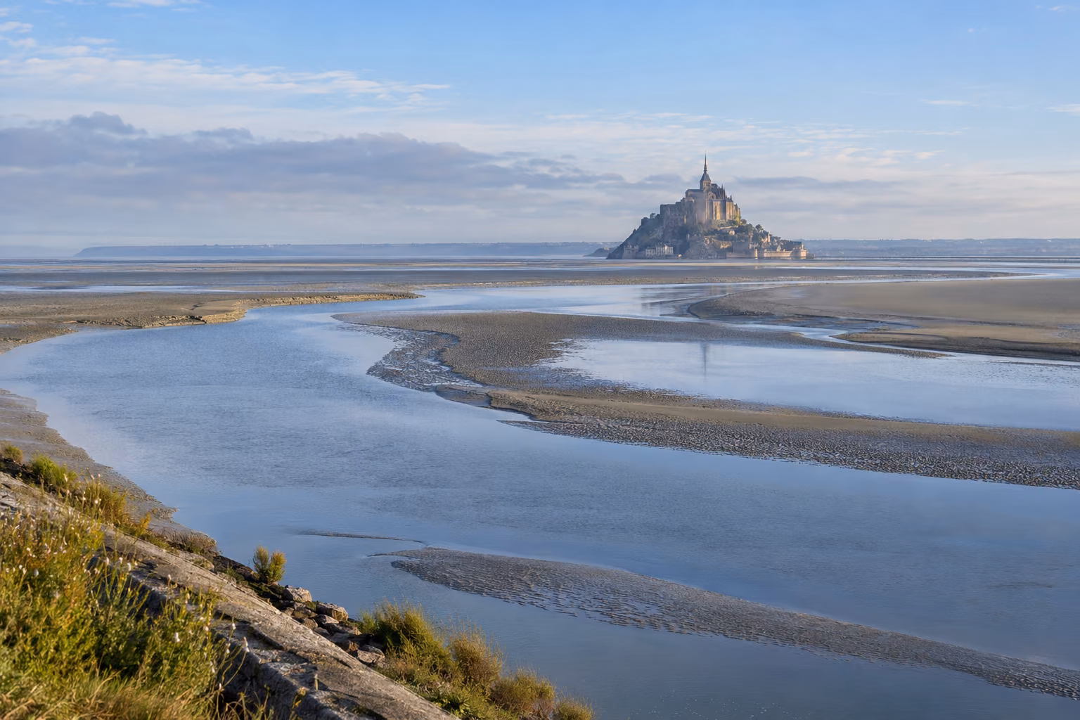 Mont-Saint-Michel al fondo, frente a canales de marea en la bahía; recreación editorial.