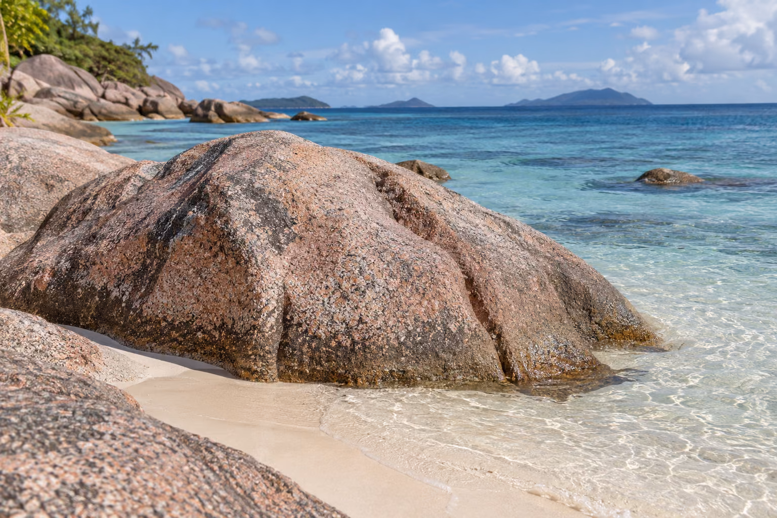 Recreación editorial de un afloramiento genérico de granito rosado junto al mar; no representa una formación concreta de La Digue.